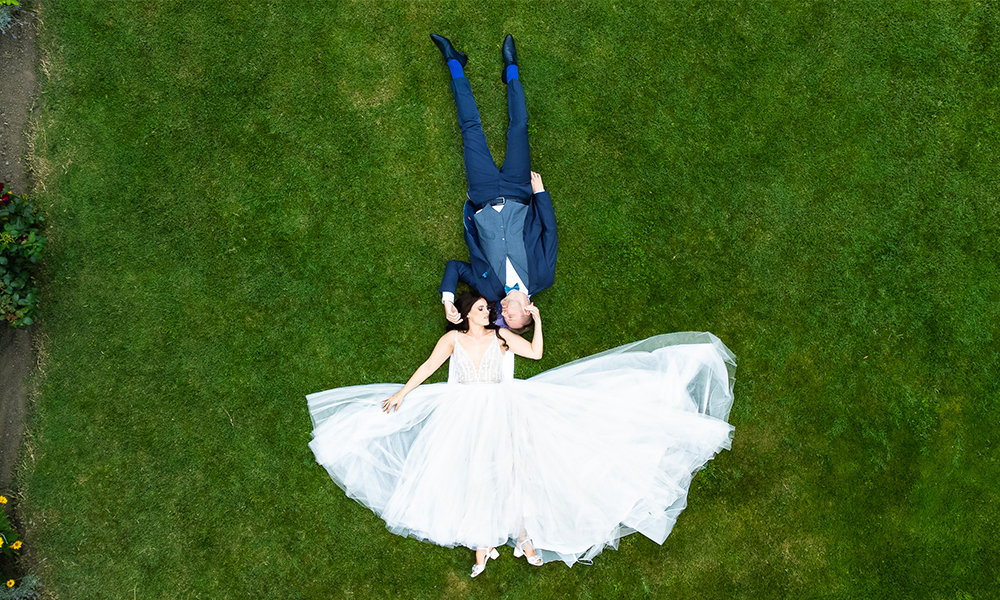 Drohnenaufnahme eines Brautpaares auf einer Wiese